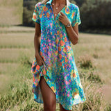 Floral summer dress with short sleeves, teal-blue base and multicolor pattern, side slit.