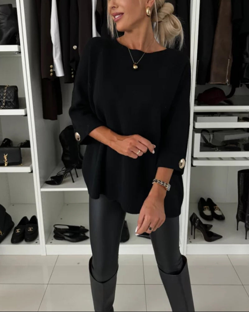 Black knit pullover with round neckline and buttoned sleeve cuffs