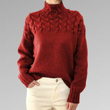 Women's cable-knit turtleneck sweater, red with raised cable-knit pattern.