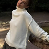 White knit turtleneck sweater with long sleeves and ribbed shoulder detail