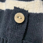 Dark knit placket detail with round tan button and textured stitch pattern.