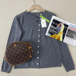 Grey knit pullover with V-neck and button front on hanger, long sleeves