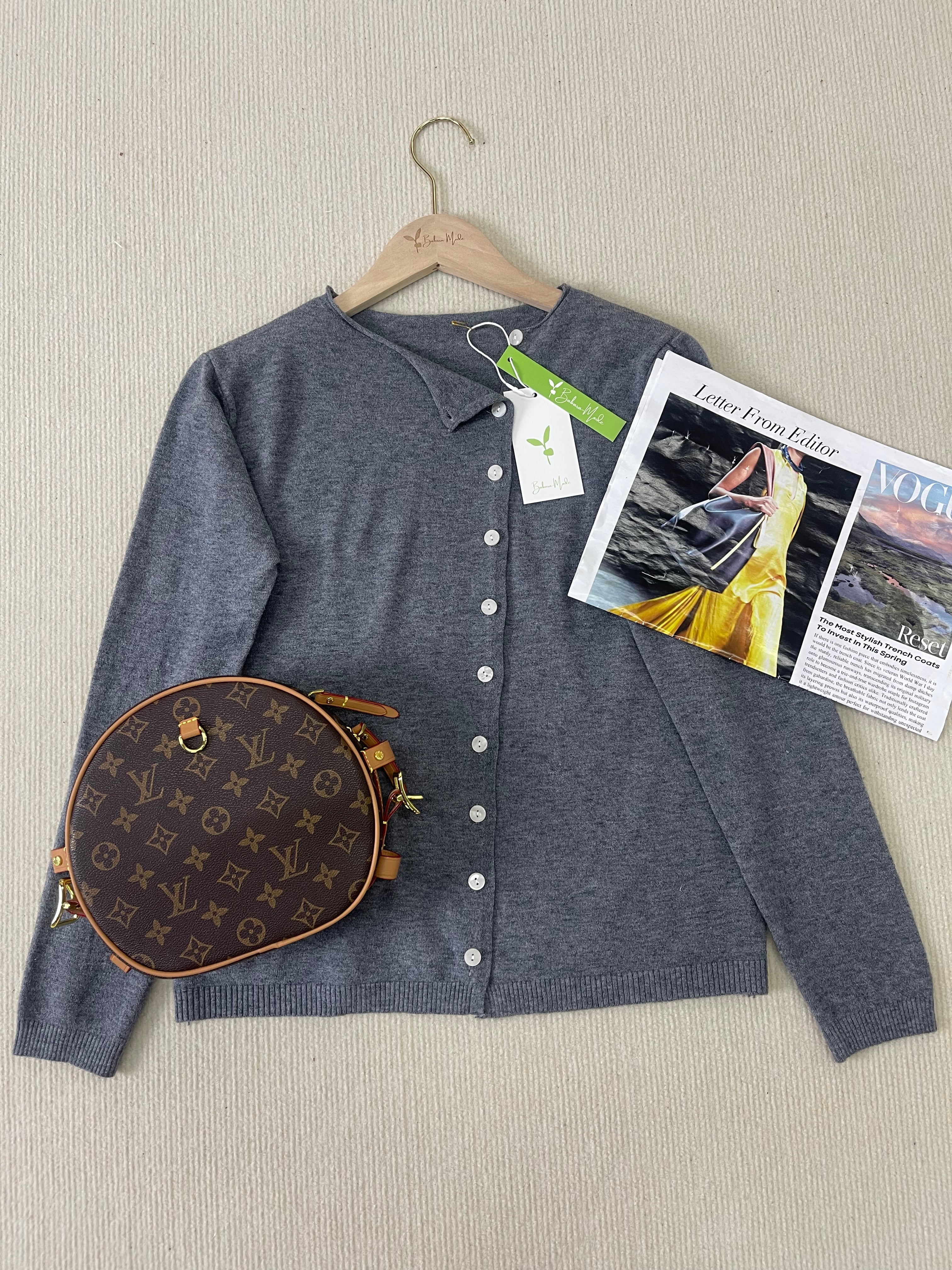 Grey knit pullover with V-neck and button front on hanger, long sleeves