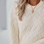 Off-white cable knit sweater with crew neckline and textured chevron pattern