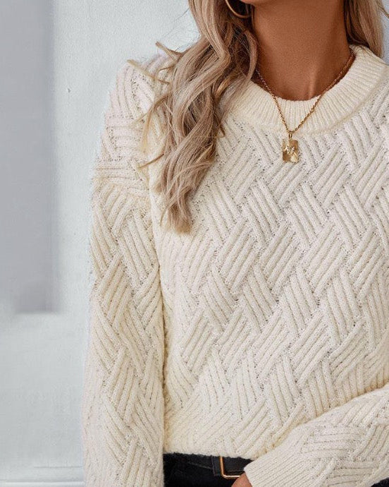 Off-white cable knit sweater with crew neckline and textured chevron pattern
