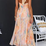 Peach watercolor halter maxi dress with crisscross back straps and flared skirt