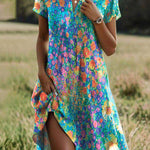 Floral short-sleeve summer dress on a teal-blue base with multicolor print and side slit.