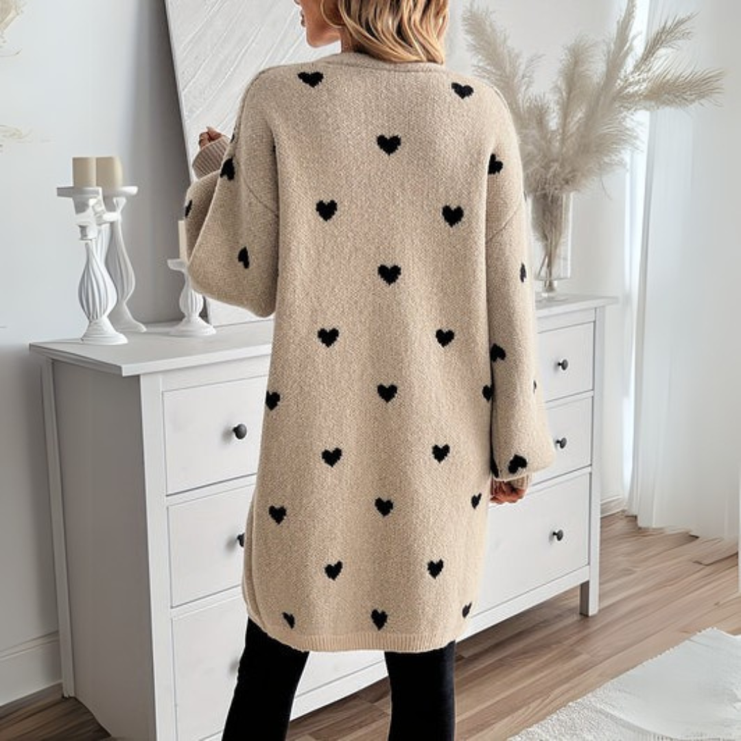 Back view of beige knit cardigan with allover black heart print and long sleeves