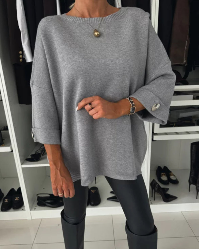 Gray knit pullover with round neckline and buttoned sleeve cuffs