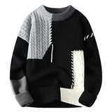 Black knit sweater with cream accents and light gray cable panel; ribbed crew neck