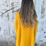 Mustard yellow V-neck pullover sweater, back view with loose knit hem.