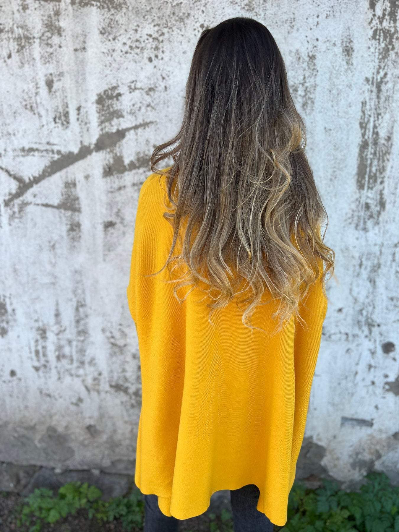 Mustard yellow V-neck pullover sweater, back view with loose knit hem.