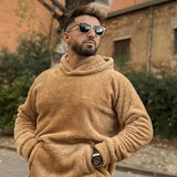 Tan fleece hoodie pullover worn by a man, hood up and hands in the front pocket.