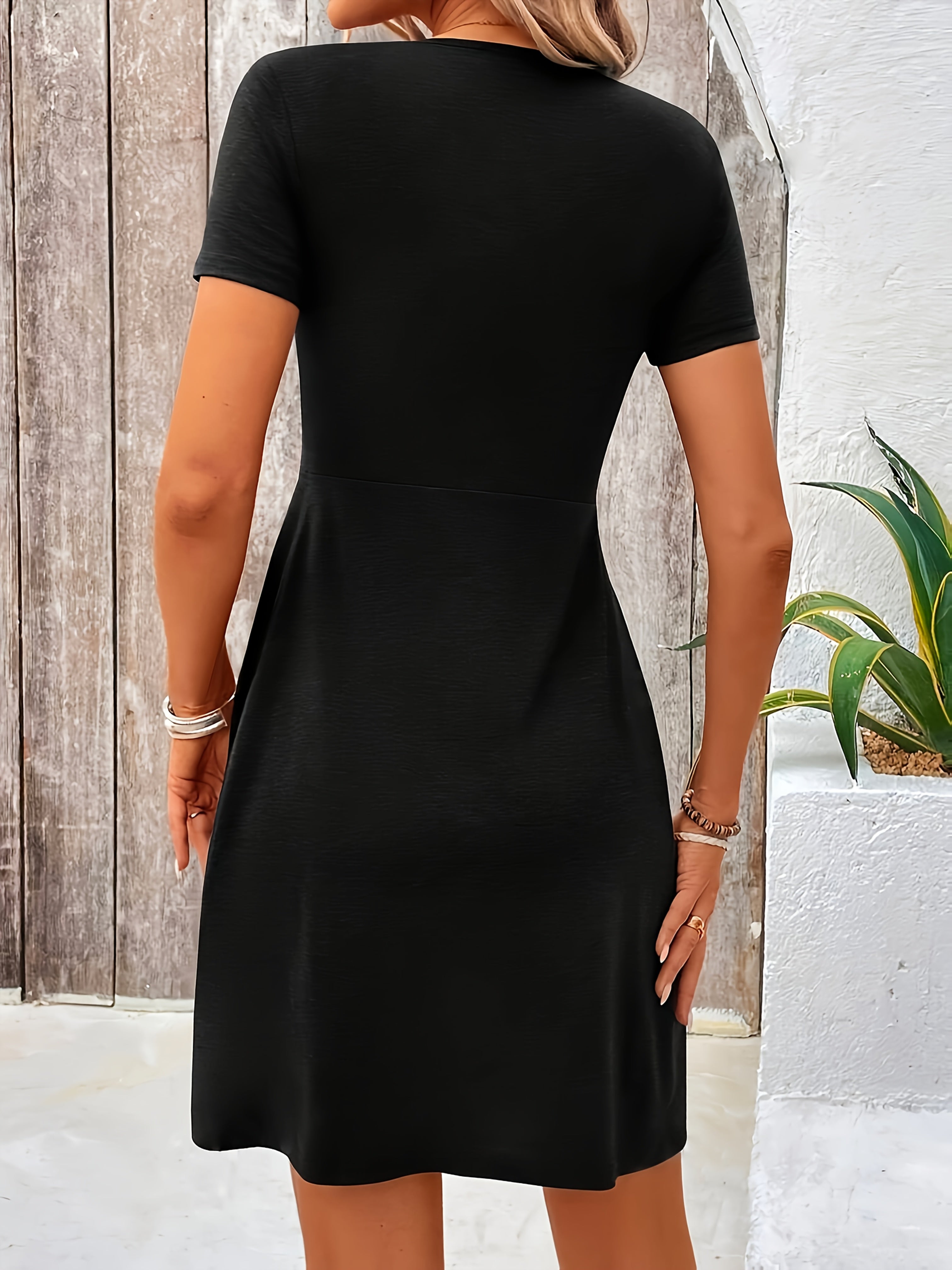 Black short-sleeve dress, back view, fitted waist and flared skirt