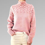 Women's cable-knit turtleneck sweater, pink with raised cable-knit front detail.