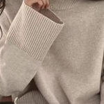 Cream knit turtleneck sweater with long sleeves, ribbed cuffs, and neckline