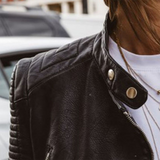 Dark leather jacket detail with snap strap collar, metal zip, and quilted texture