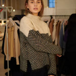 Beige turtleneck sweater with black-and-cream chevron panel and long sleeves