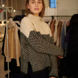 Beige turtleneck sweater with black-and-cream chevron panel and long sleeves