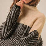 Beige turtleneck sweater with black-and-white chevron knit pattern near collar
