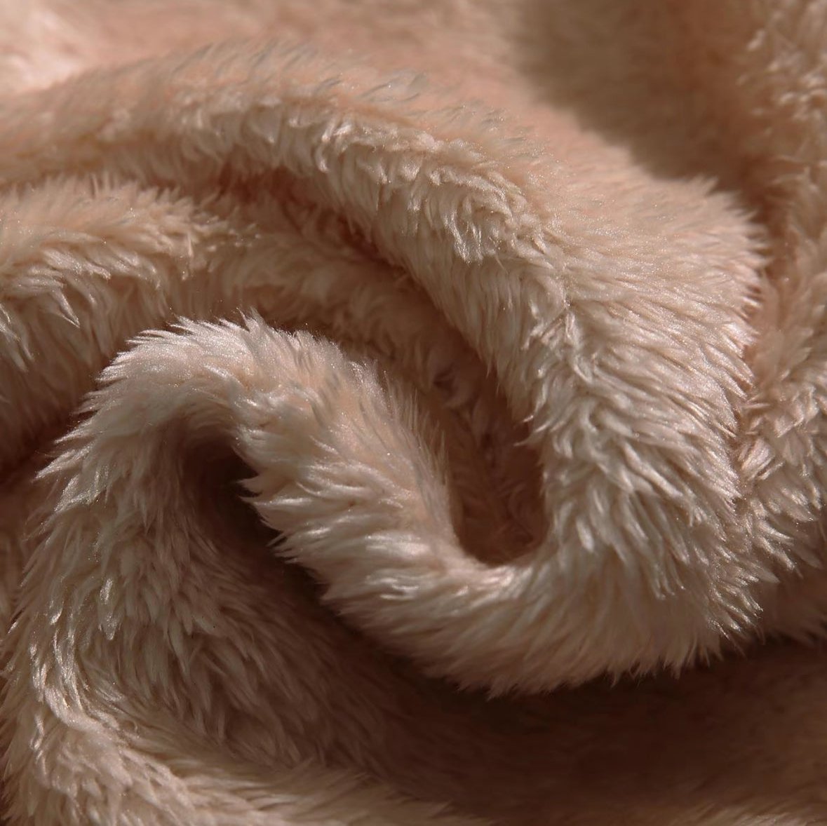 Close-up of tan fleece fabric texture with soft, curly pile.