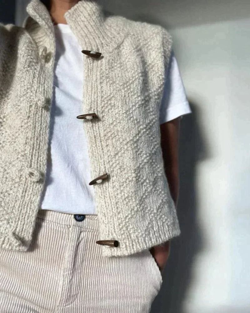 Cream knit sleeveless cardigan showing button placket and curved hem