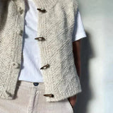 Cream knit sleeveless cardigan showing button placket and curved hem