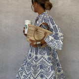 Blue-and-white patterned V-neck mini dress with long sleeves and ruffled, flared hem.