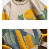 Beige knit crew pullover closeup with cat graphic and ribbed cuffs
