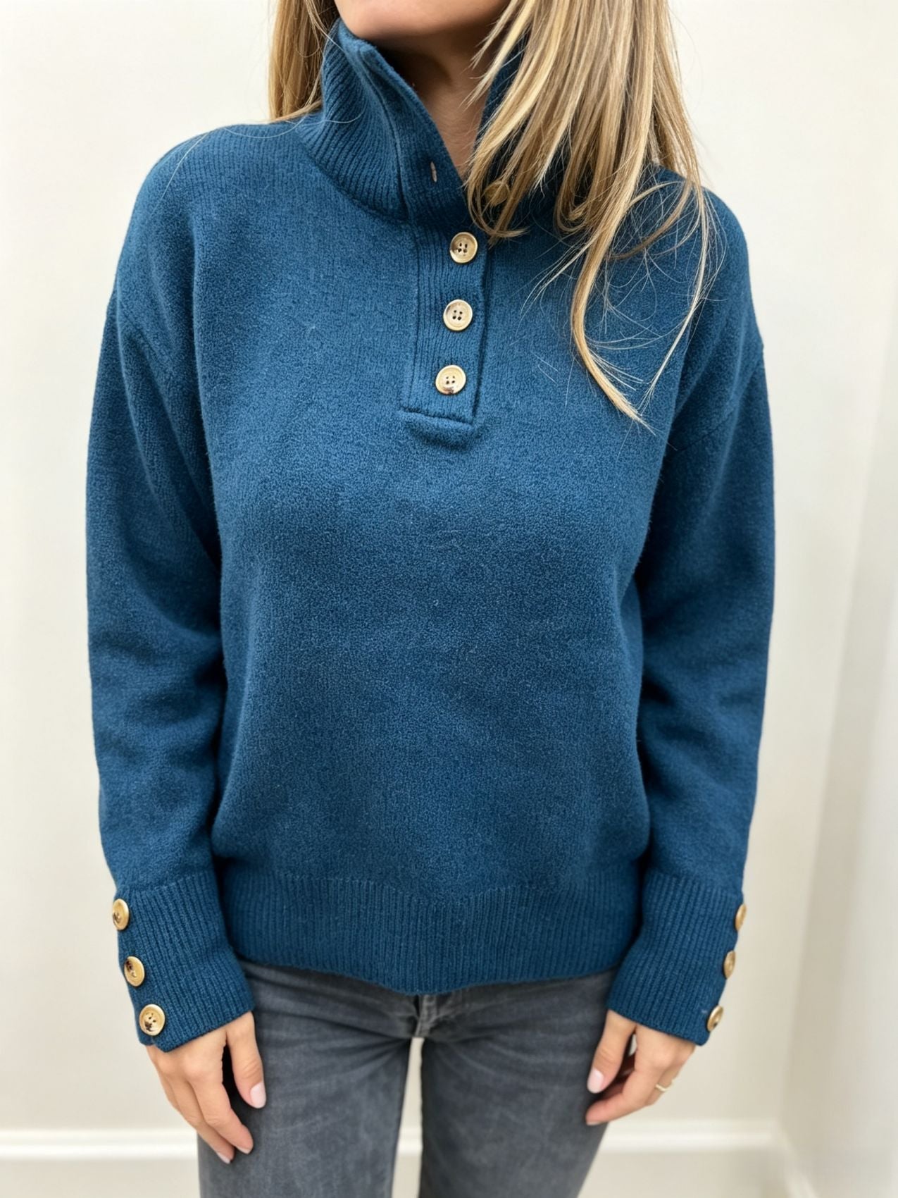 Blue knit long-sleeve pullover with button placket at the neckline and ribbed cuffs