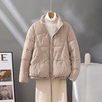 Women's short quilted jacket in light beige, high collar, zip front, flap pockets.