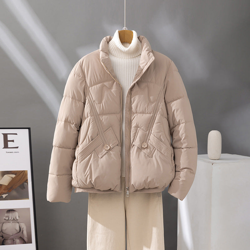 Women's short quilted jacket in light beige, high collar, zip front, flap pockets.