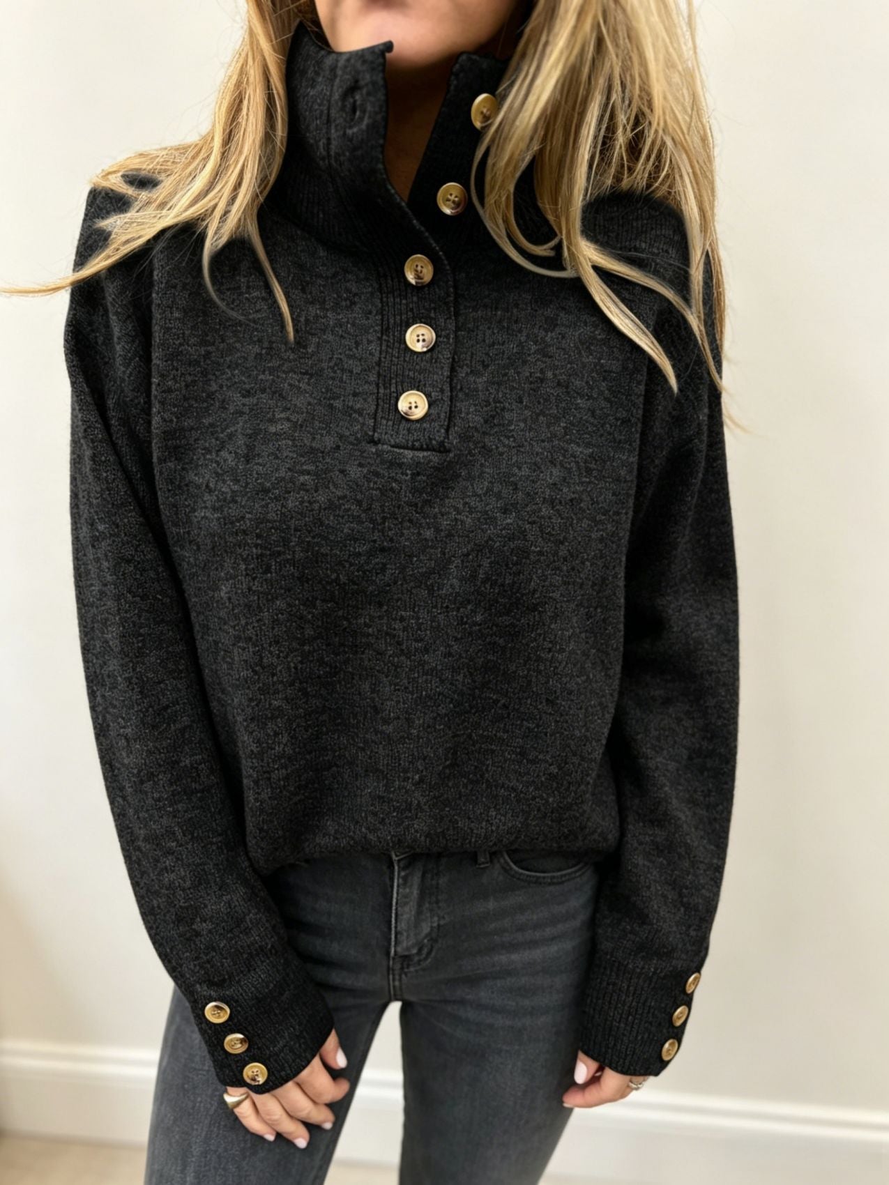 Black knit long-sleeve pullover with button placket, stand collar and ribbed hem