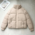 Light beige short quilted puffer jacket with high stand collar, zip front, D-ring strap pockets