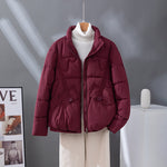 Women's short quilted jacket in burgundy, high collar, zip front, flap pockets.