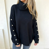 Oversized dark navy knit turtleneck pullover with buttoned cuffs, long sleeves