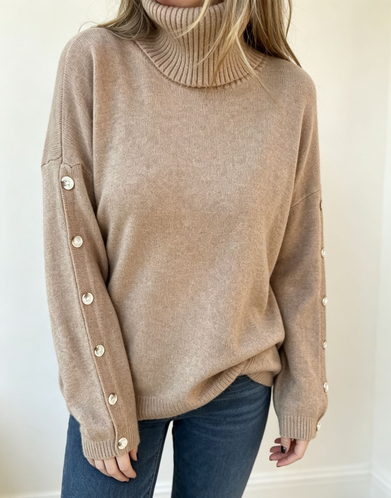 Oversized beige knit turtleneck pullover with buttoned cuffs, long sleeves