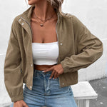 Cropped long-sleeve beige jacket with stand collar, snap front, and side pockets in textured fabric.
