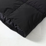 Black quilted parka fabric close-up with long hem and snap button placket