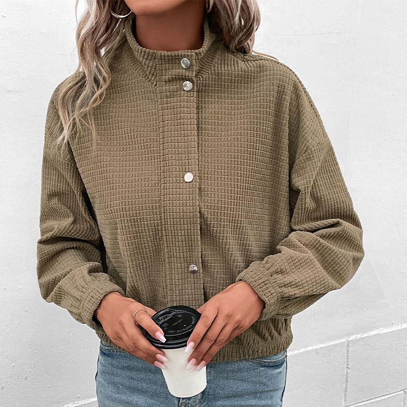 Cropped long-sleeve jacket in olive textured fabric with button front and side pockets.