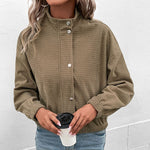 Cropped long-sleeve jacket in olive textured fabric with button front and side pockets.