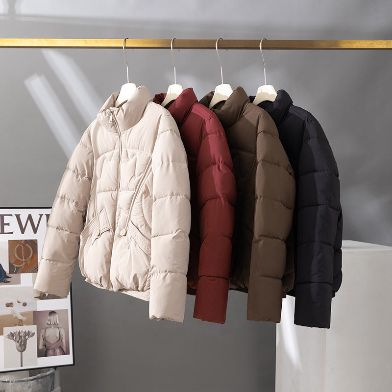 Women's short quilted jacket in cream, high collar, zip front, flap pockets.