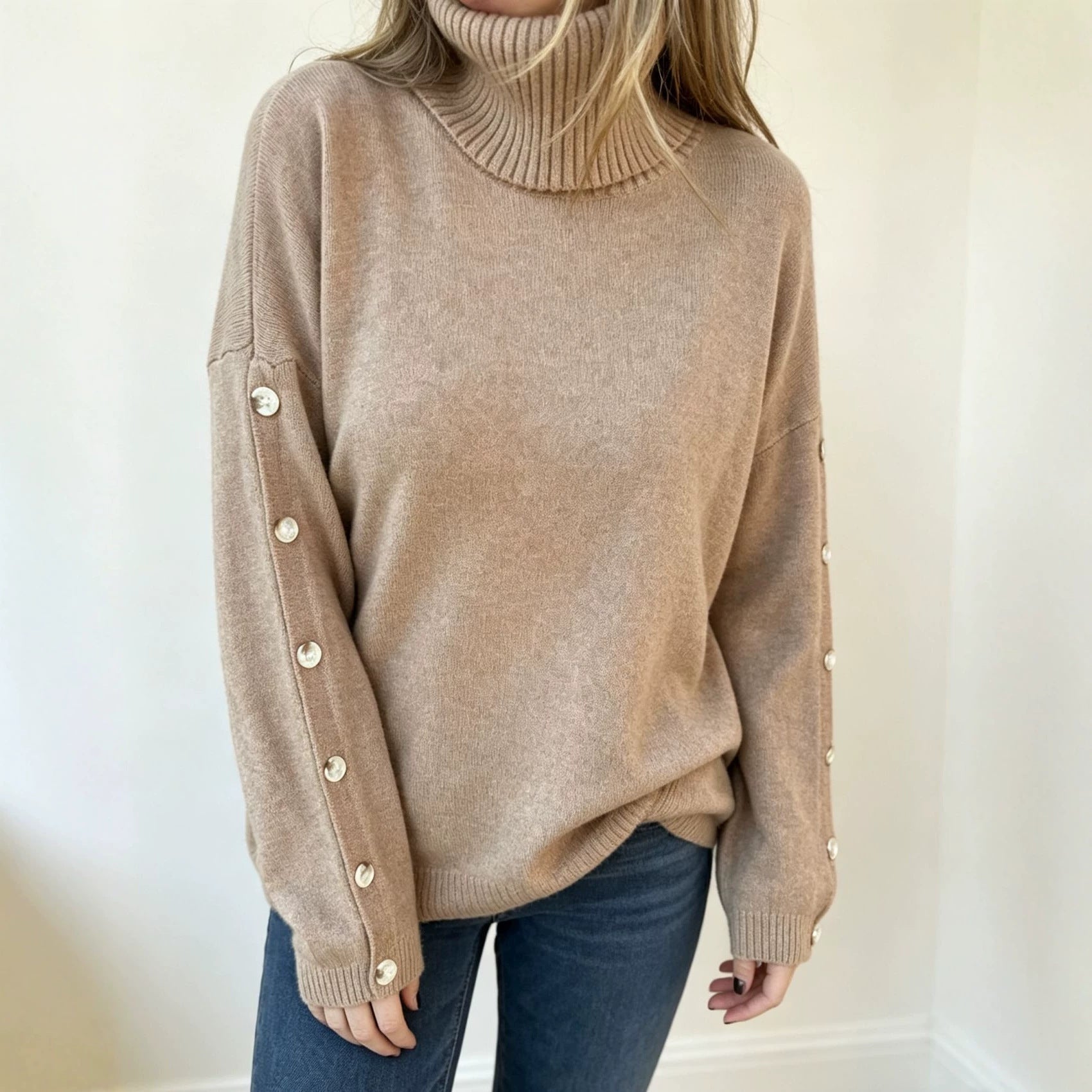 Oversized beige knit turtleneck pullover with buttoned cuffs, long sleeves