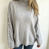 Oversized light gray knit turtleneck pullover with buttoned cuffs, long sleeves