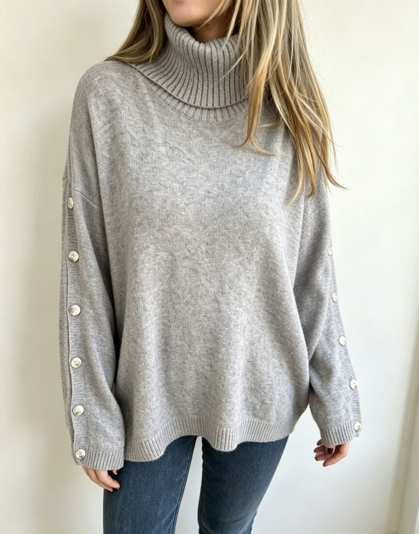 Oversized light gray knit turtleneck pullover with buttoned cuffs, long sleeves
