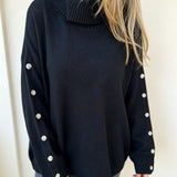 Oversized black knit turtleneck pullover with buttoned cuffs, long sleeves