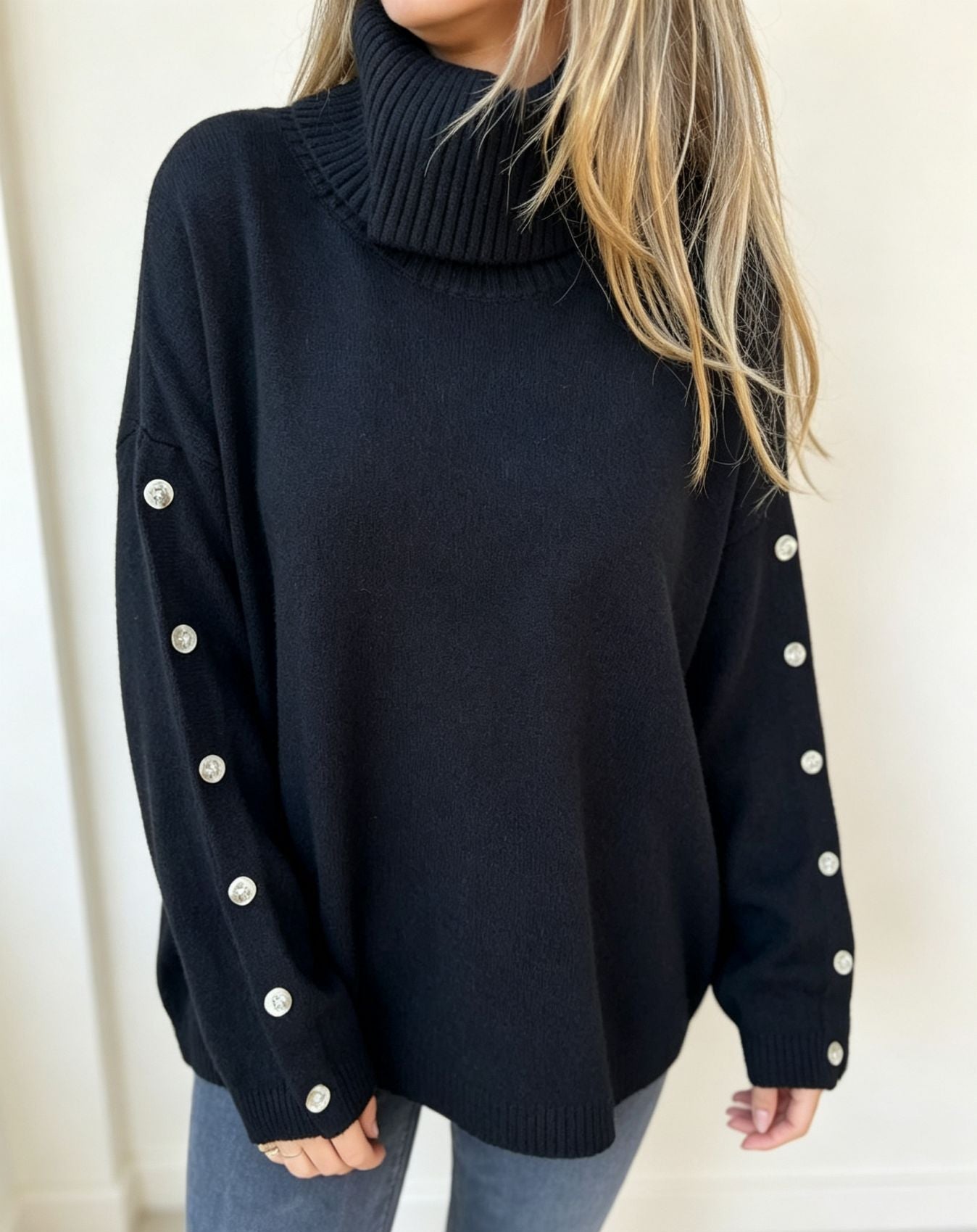 Oversized black knit turtleneck pullover with buttoned cuffs, long sleeves