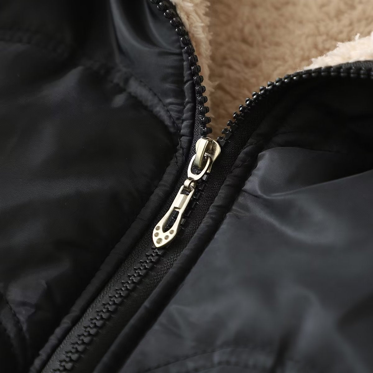 Black jacket zipper close-up with white metal pull and stitched placket