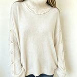 Oversized white knit turtleneck pullover with buttoned cuffs, long sleeves