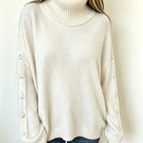 Oversized white knit turtleneck pullover with buttoned cuffs, long sleeves
